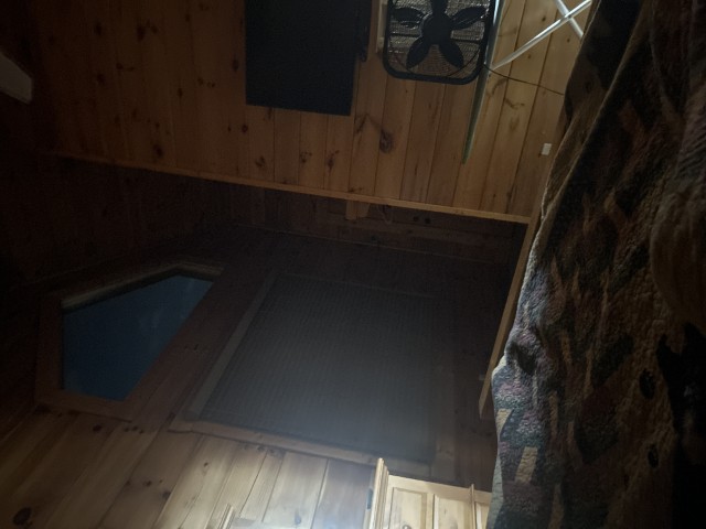 A dark hallway in a wooden cabin leading into shadows.